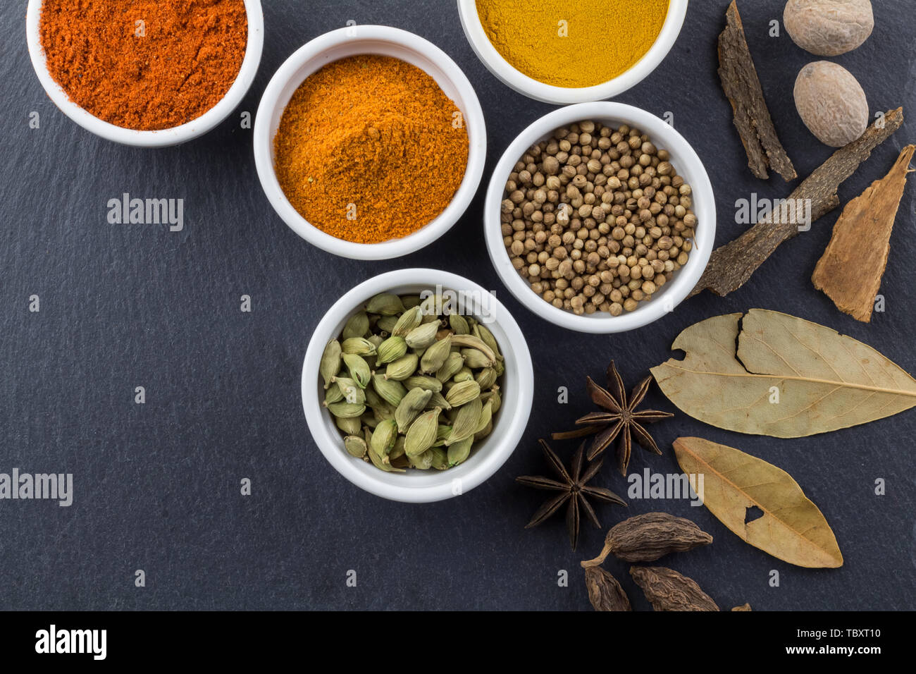 Spices in little white bowls on black slate background - Indian spice top view photo with space for text Stock Photo