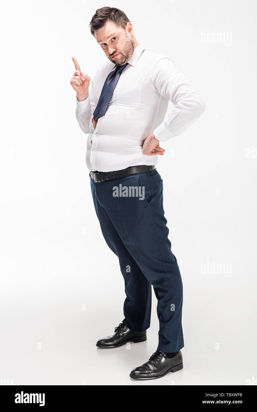 overweight man in tight formal wear pointing with finger and looking at ...