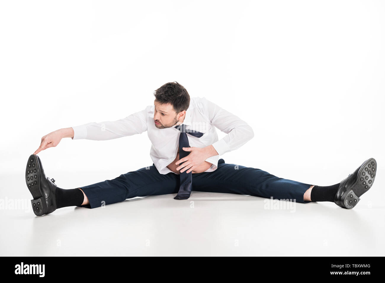 overweight man in tight formal wear sitting and stretching on white Stock Photo