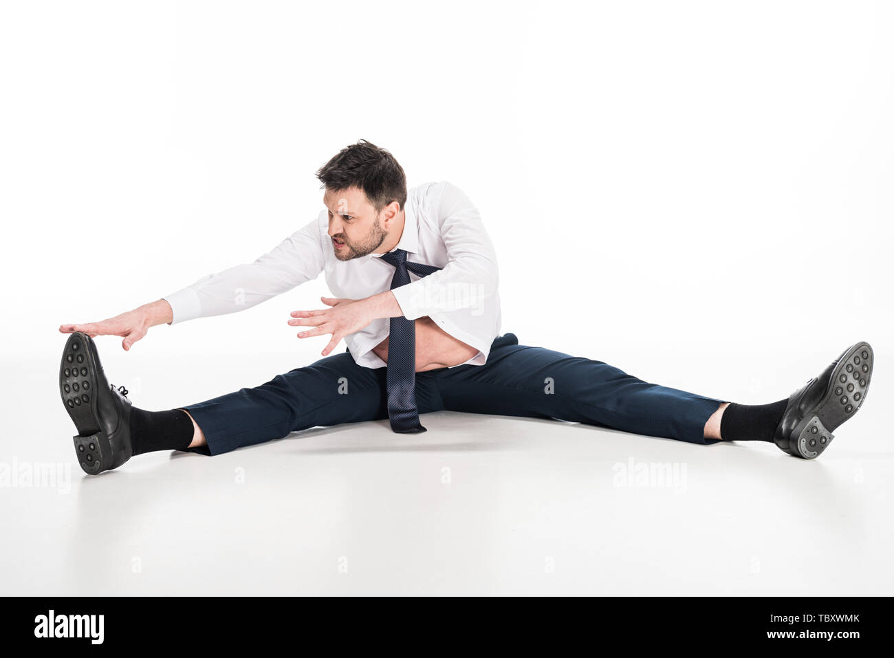 overweight man in tight formal wear sitting and stretching on white Stock Photo