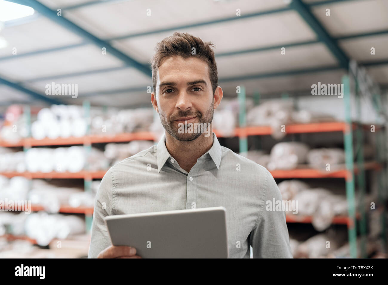 Warehouse manager smiling while using a digital tablet  Stock Photo