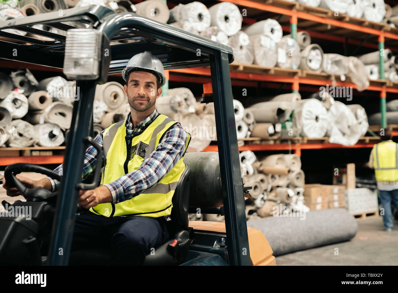 Smiling worker using a forklift to move warehouse stock Stock Photo