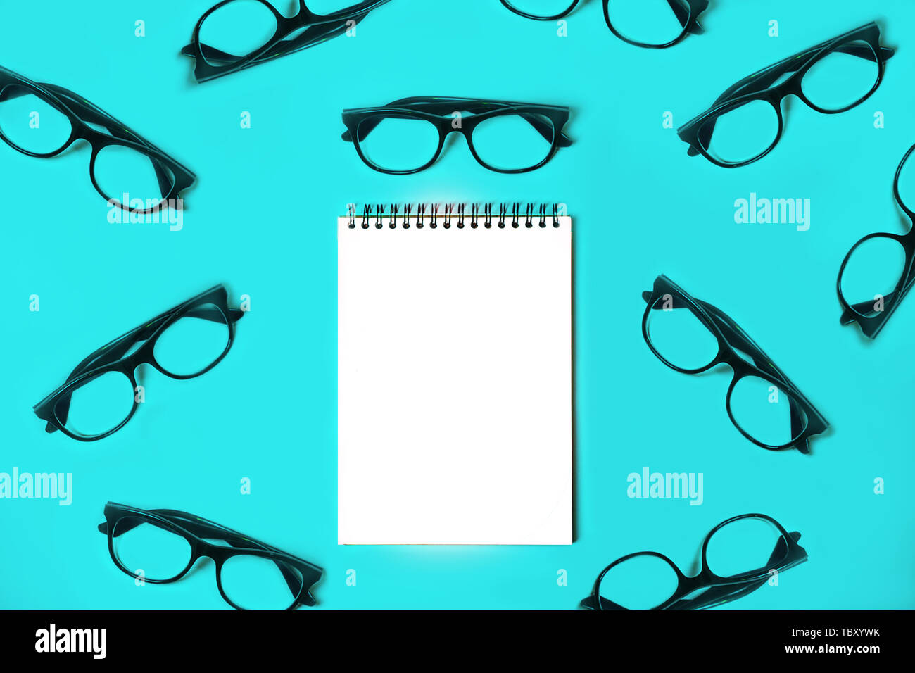 Notepad with trendy glasses on blue background. Stock Photo