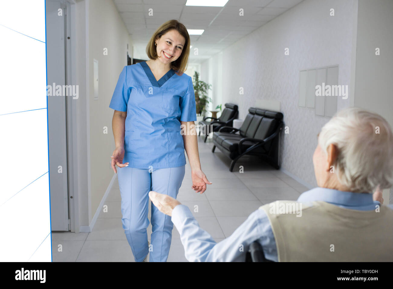 nurse smiling to senior man in wheelchair at nursing home Stock Photo