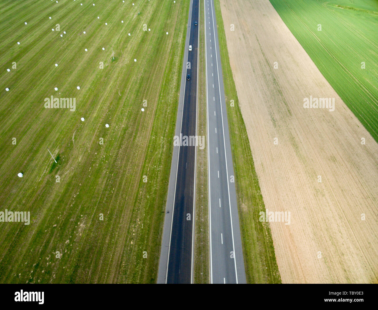 Aerial top view of asphalt road through a green field in summer in ...