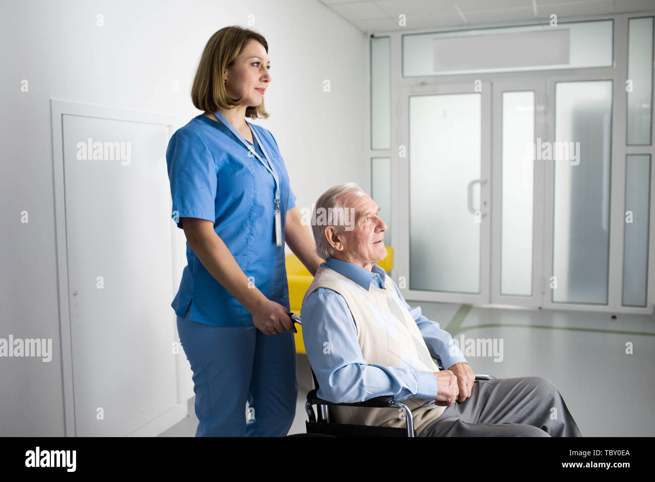 Thoughtful nurse pushing senior patient in wheelchair at hospital Stock Photo