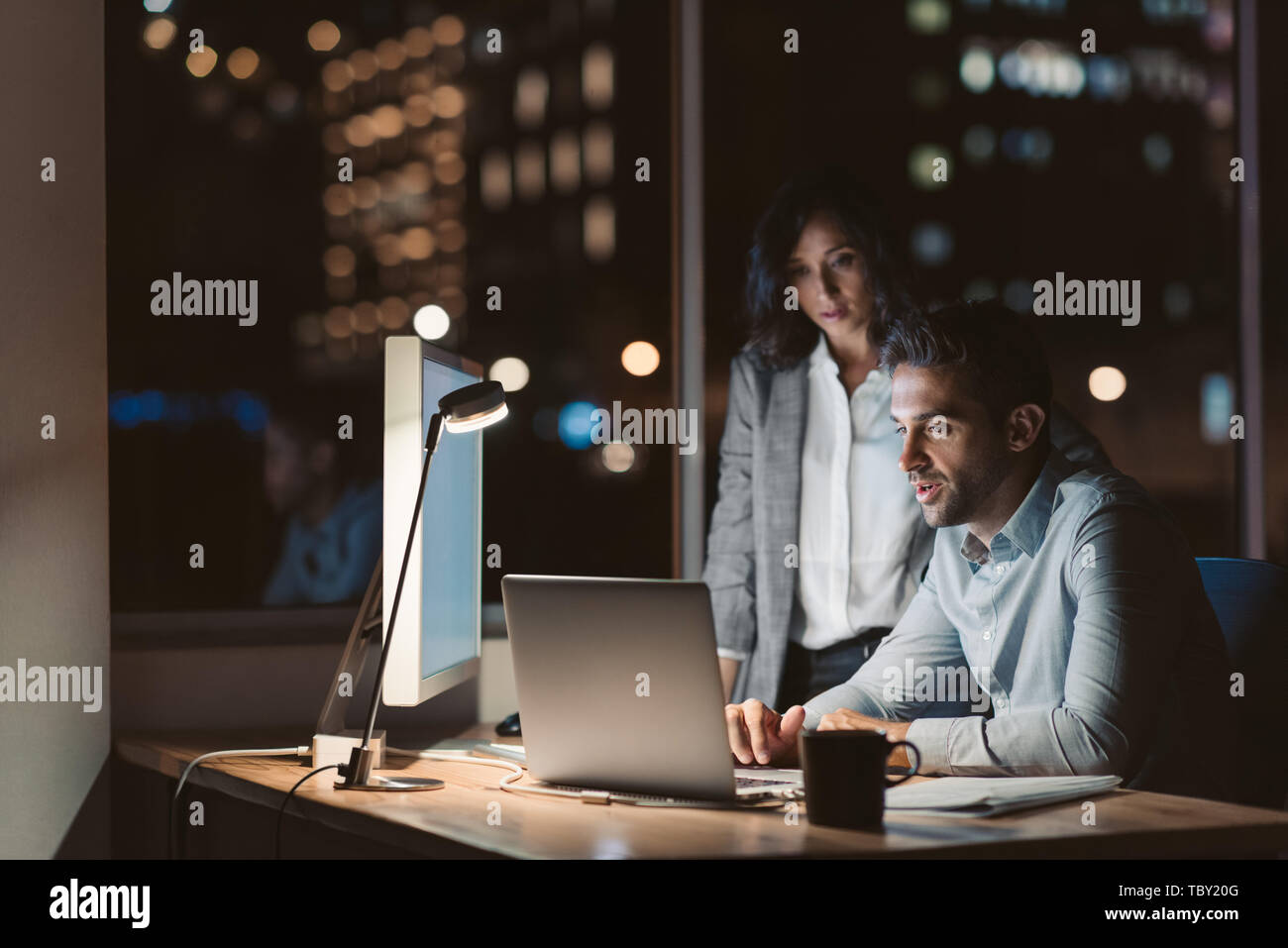 Two focused colleagues working in an office late at night Stock Photo