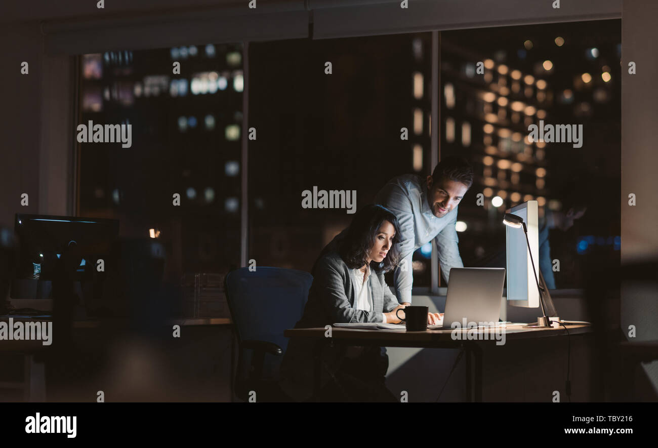 Young business colleagues working overtime together at an office desk Stock Photo