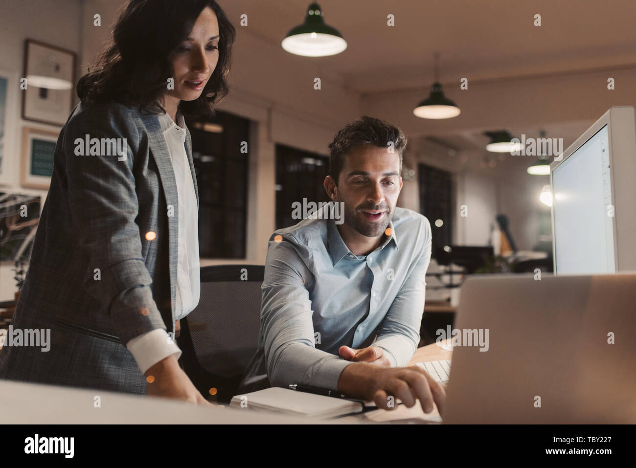Two young businesspeople working late in an office together Stock Photo