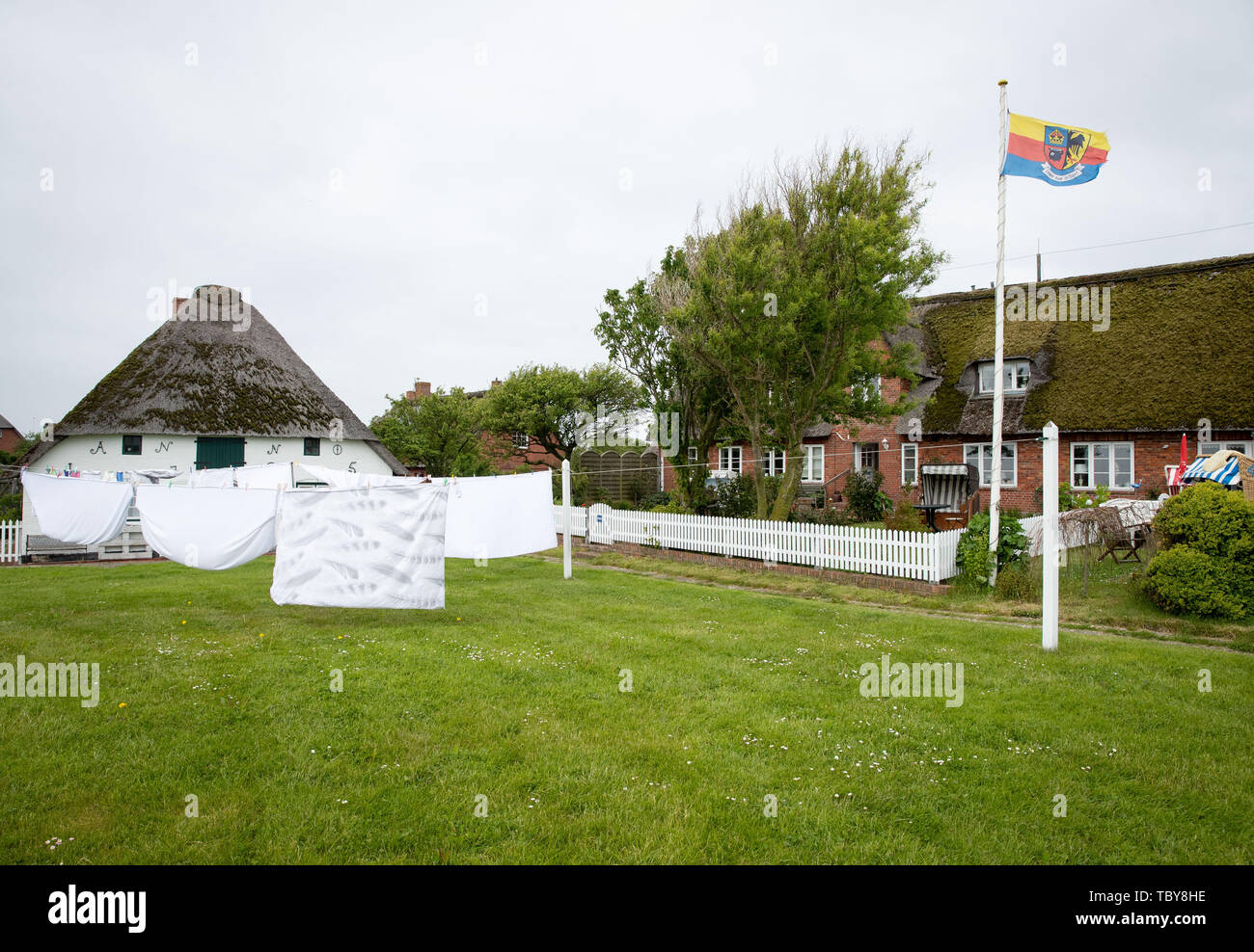31 May 2019, Schleswig-Holstein, Dagebüll: Laundry dries in front of a house on the Hallig Langeness. The 11,500 square kilometre Wadden Sea stretches over 500 kilometres of coastline from Esbjerg in Denmark to Den Helder in the Netherlands. Schleswig-Holstein's share of the World Heritage Site is 4400 square kilometres, or more than one third. Photo: Christian Charisius/dpa Stock Photo
