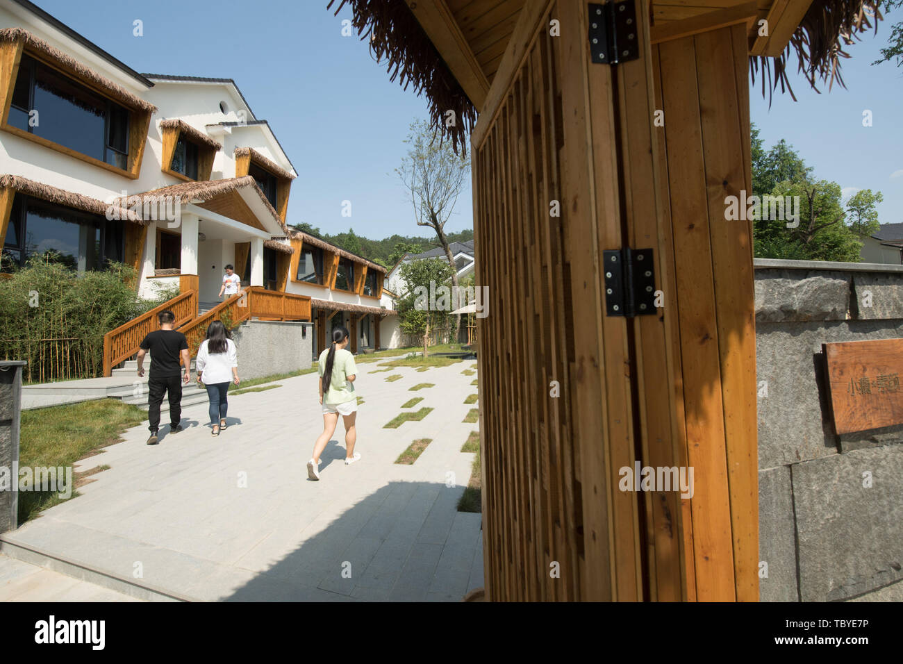 (190604) -- ANJI, June 4, 2019 (Xinhua) -- People walk into a guesthouse designed by Chen Gu in Anji, east China's Zhejiang Province, June 4, 2019. Chen Gu, born in 1971, has been working in design industry for more than 20 years. He started to re-design village houses after returning back to his hometown Anji. In 2014, Chen renovated a group of residential houses with the support of the local government. Since then, five guesthouses have been renovated and put into use. On his effort, the residential area once fallen has gradually become a guesthouse village equipped with accommodation, dinin Stock Photo