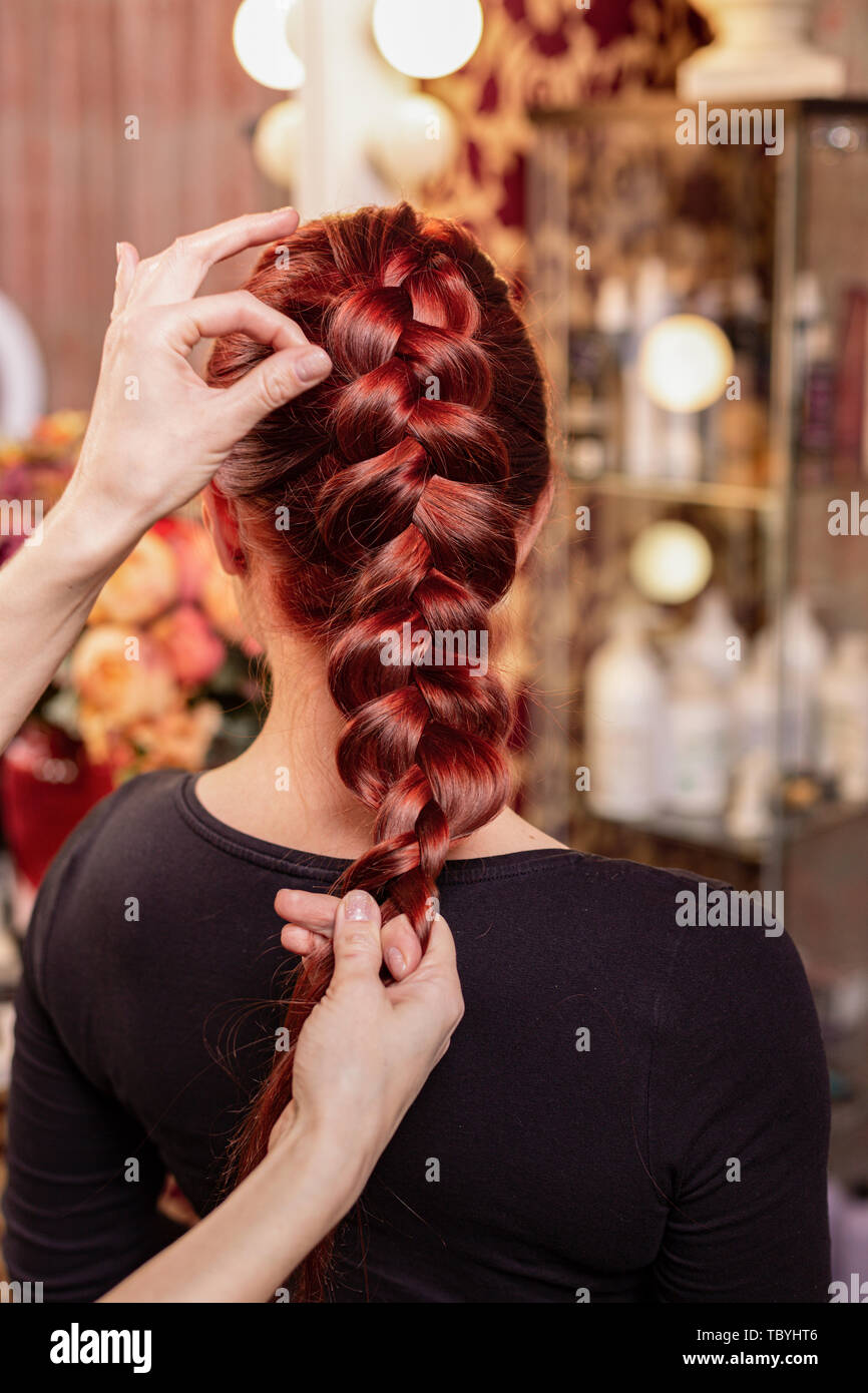 Beautiful, red-haired girl with long hair, hairdresser weaves a French braid,  in a beauty salon. Professional hair care and creating hairstyles Stock  Photo - Alamy