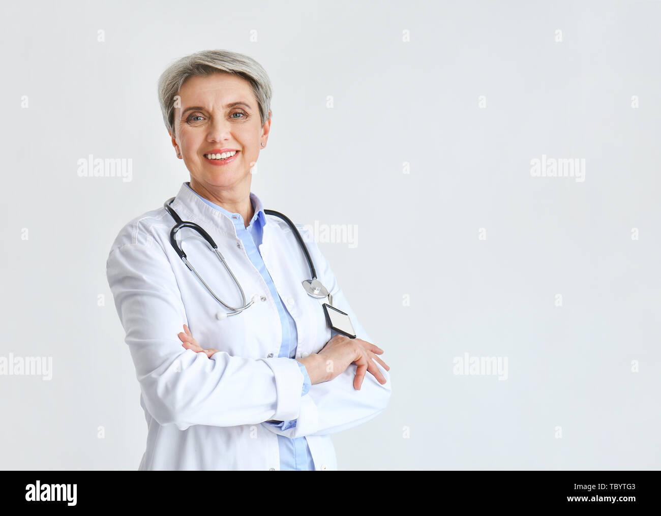 Mature female doctor on light background Stock Photo - Alamy