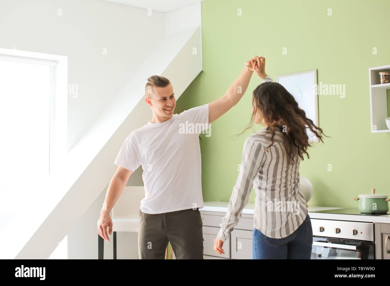 Adorable loving couple dancing in kitchen at home Stock Photo