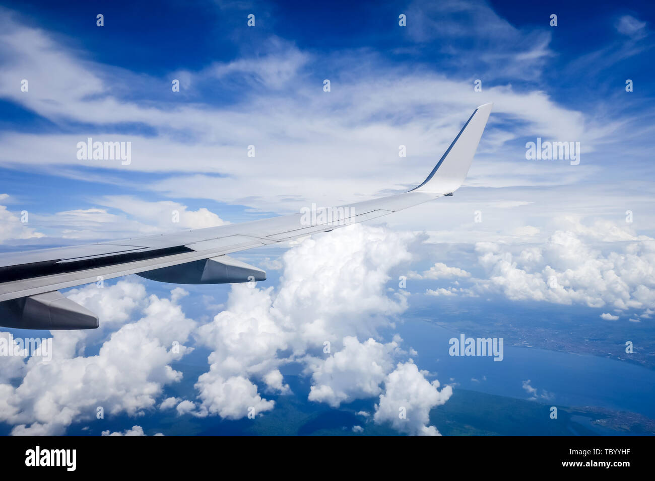 Airplane flying in a blue sunny sky above clouds Stock Photo - Alamy
