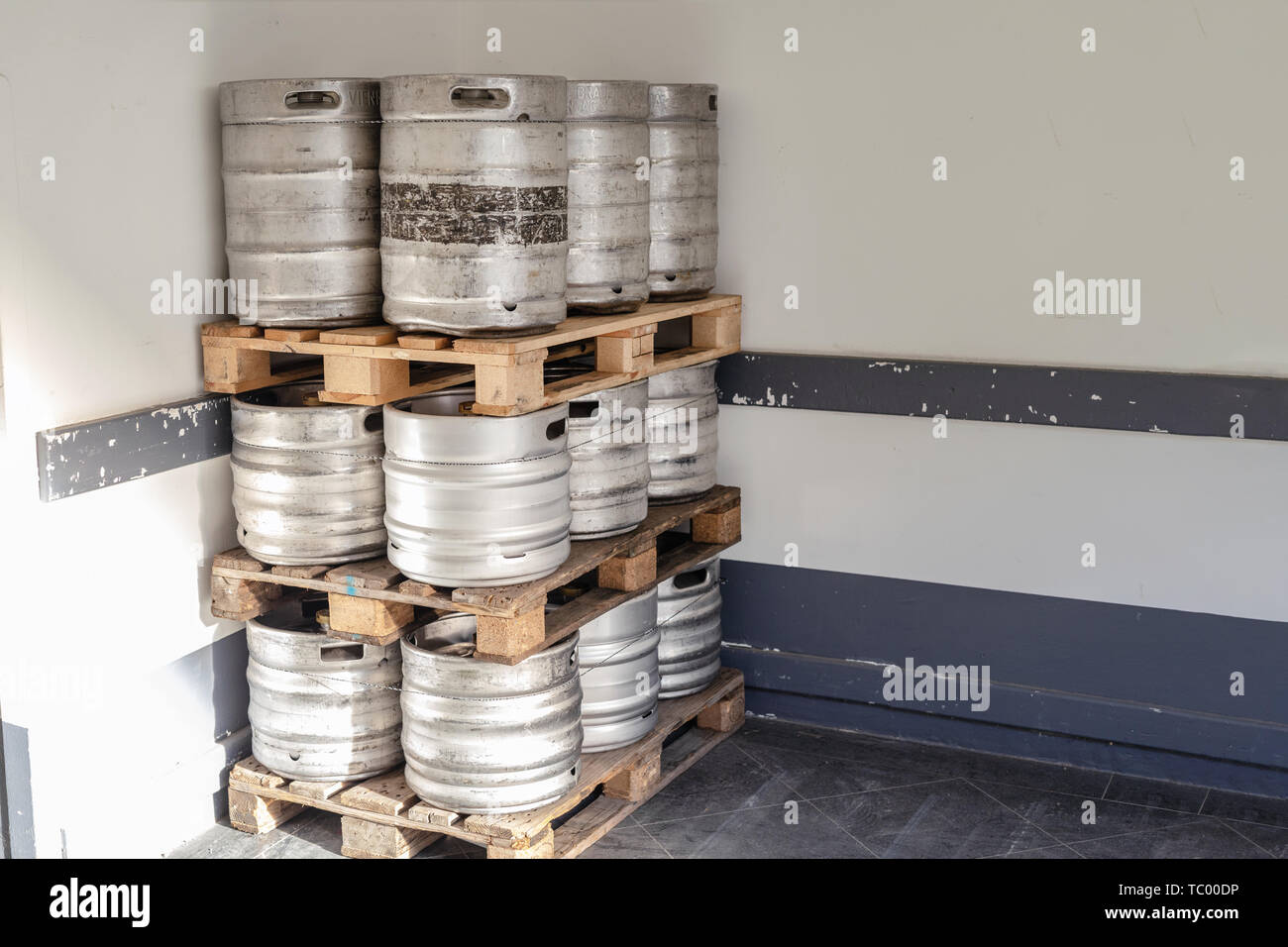 Used metal beer keg barrel on wooden pallets in corner of warehouse