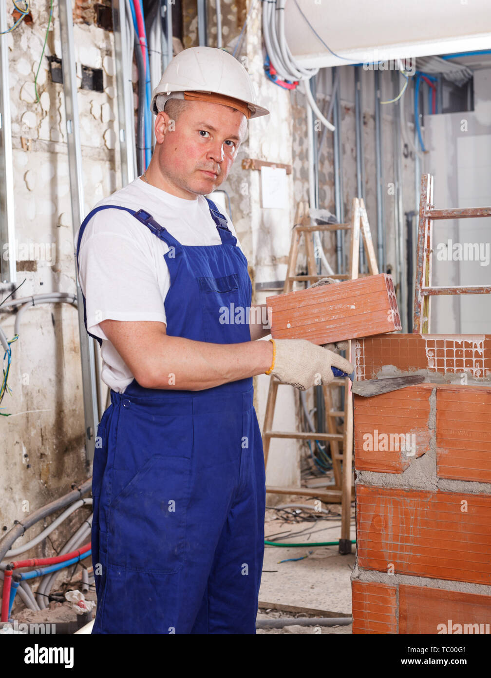 Professional builder mason installing red brick inside building in process of construction Stock Photo