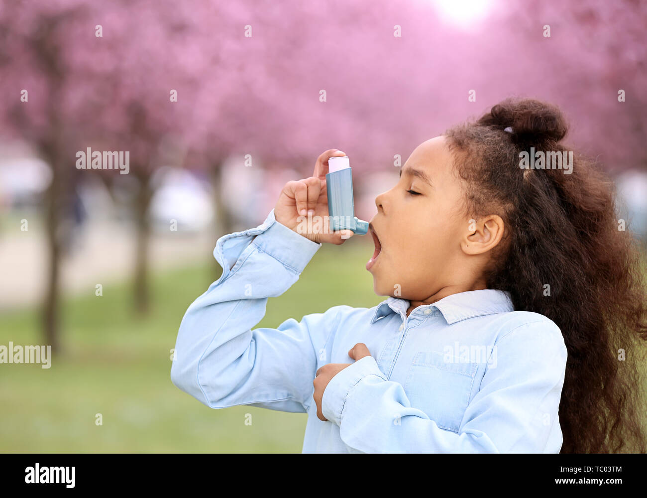 African-American girl with inhaler having asthma attack outdoors on ...
