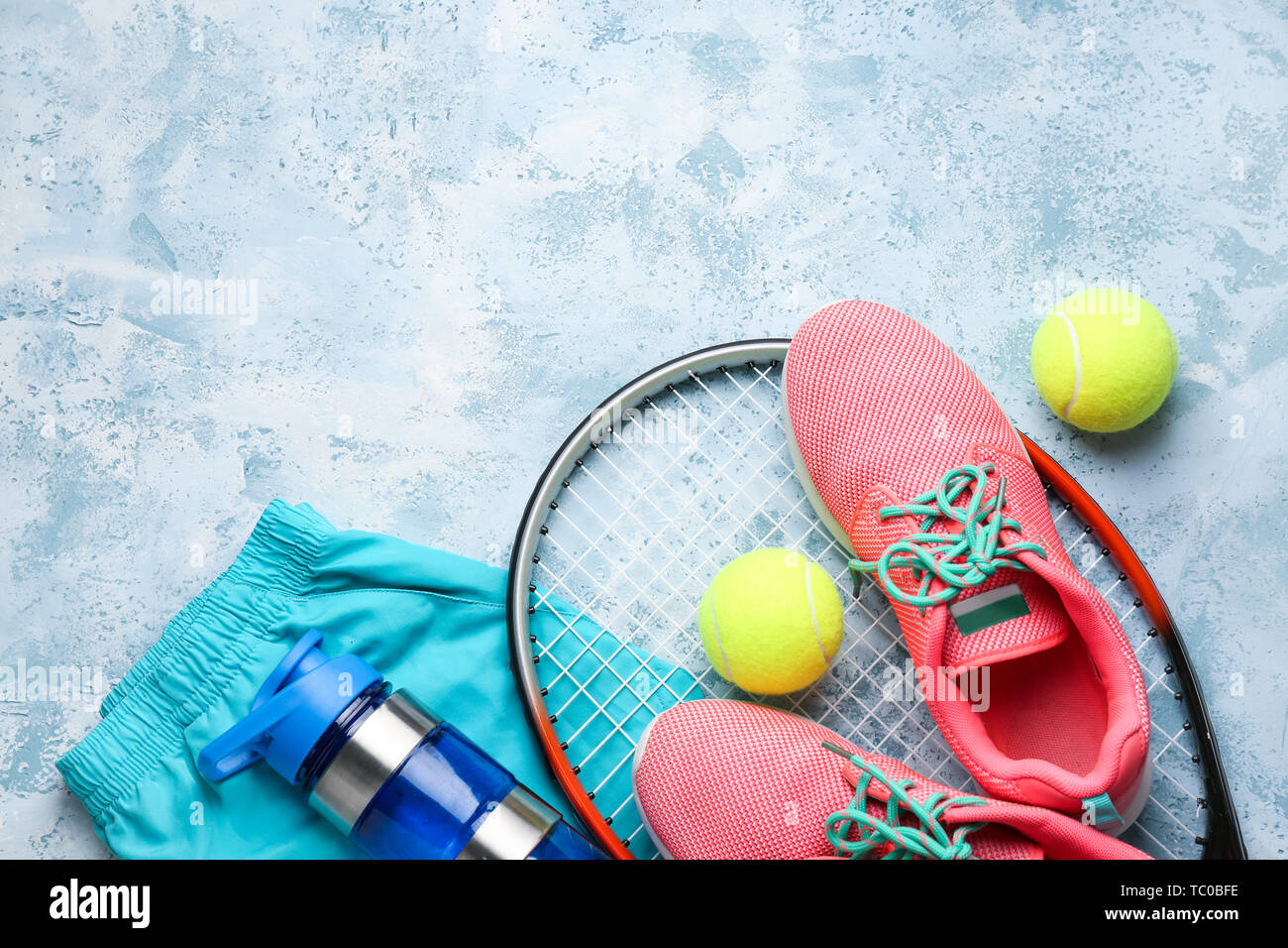 Tennis racket, shoes, clothes, bottle of water and balls on color background Stock Photo