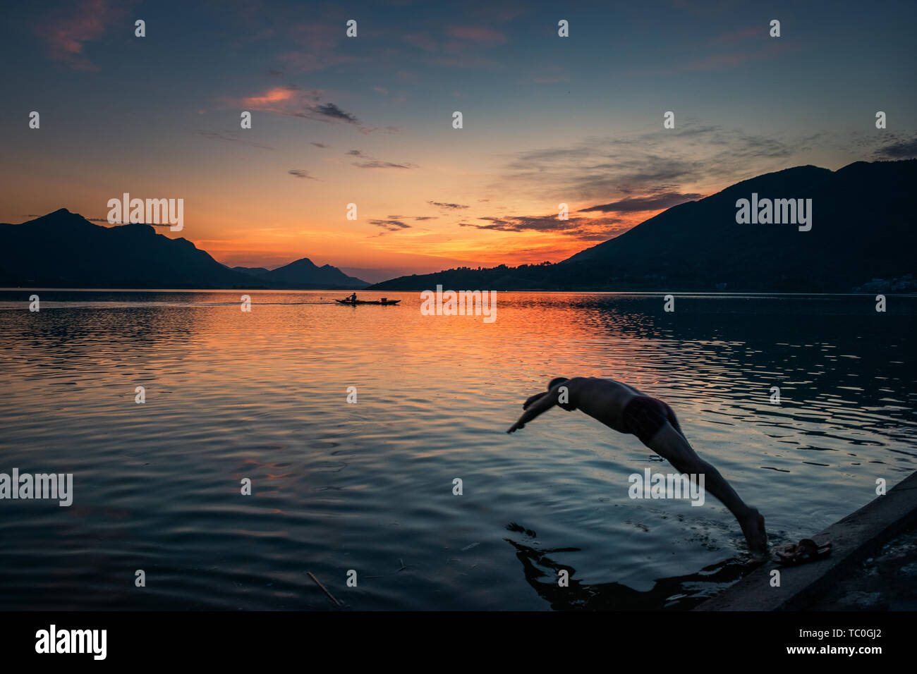 A swimmer leaps into the water in the sunset of the Fushui Reservoir Stock Photo