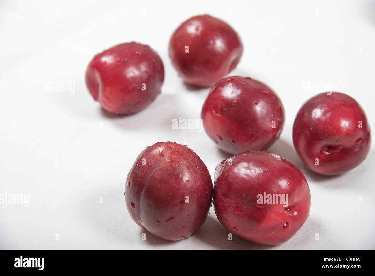 Casually laid red plum fruit on white background Stock Photo