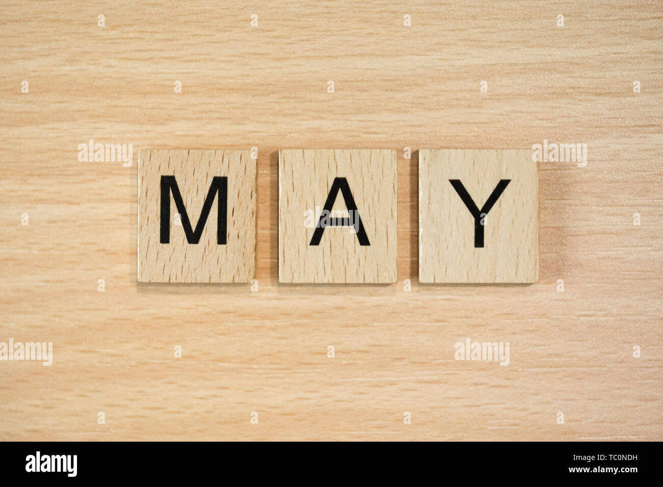 The word March, spelt out using wooden tiles on a wood effect background. Stock Photo