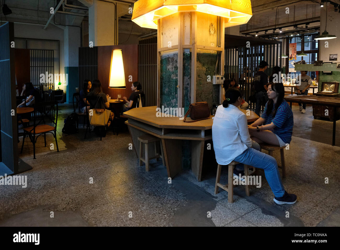 People sit in a cafe inside a ware house of a former tobacco factory  converted into a multifunctional cultural complex named Songshan Cultural  and Creative Park which its aim is to establish