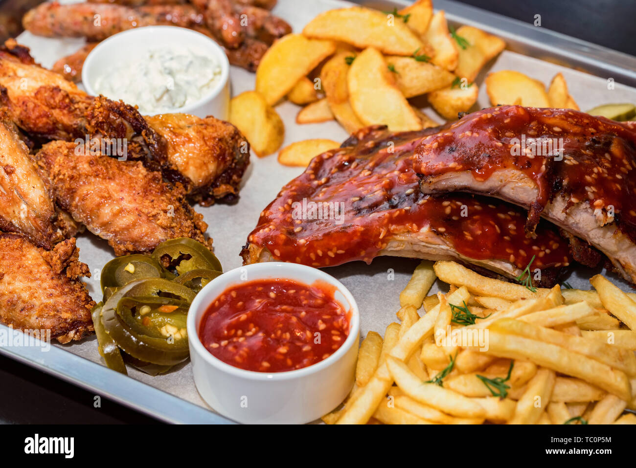 Dish of mixed meats. Grilled ribs, chicken wings and sausages with