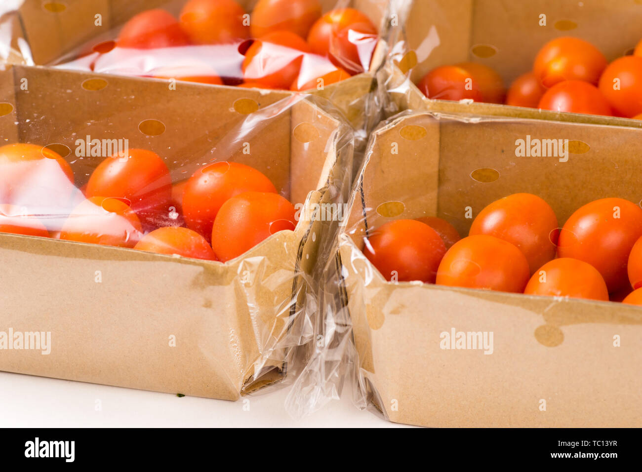 ripe cherry tomatoes packages in box and plastic close up and isolated on white background Stock Photo