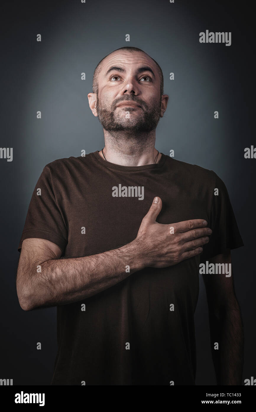 Satisfied and proud man posing with his hand over his heart. Studio portrait. Stock Photo