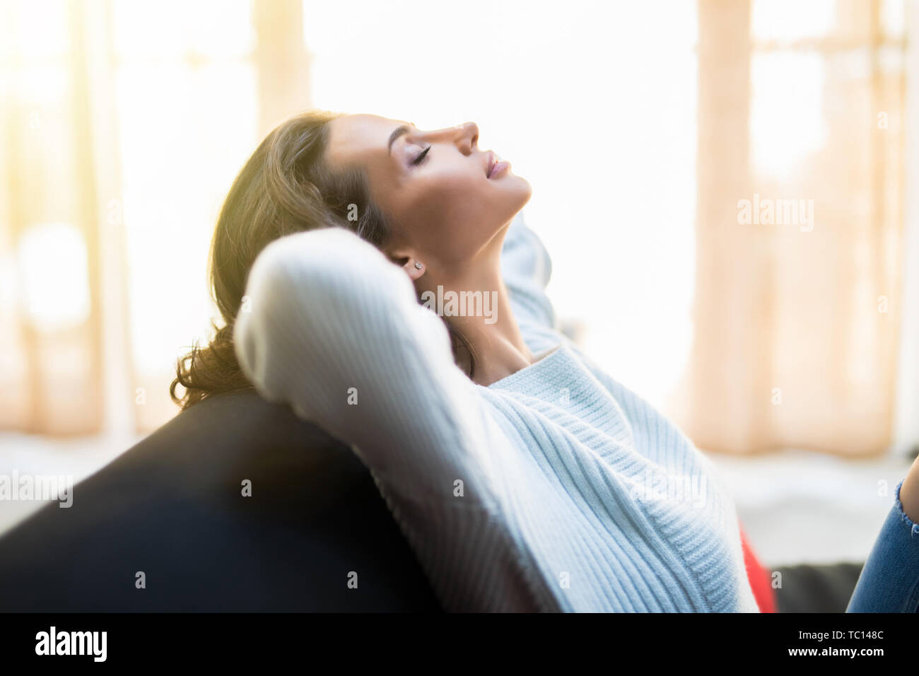 Closeup of a smiling young woman lying on couch Stock Photo - Alamy