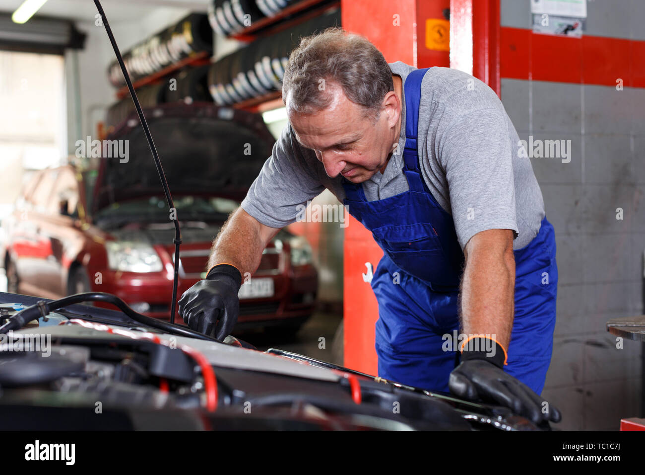 Professional mature man car mechanician repairing car in auto repair