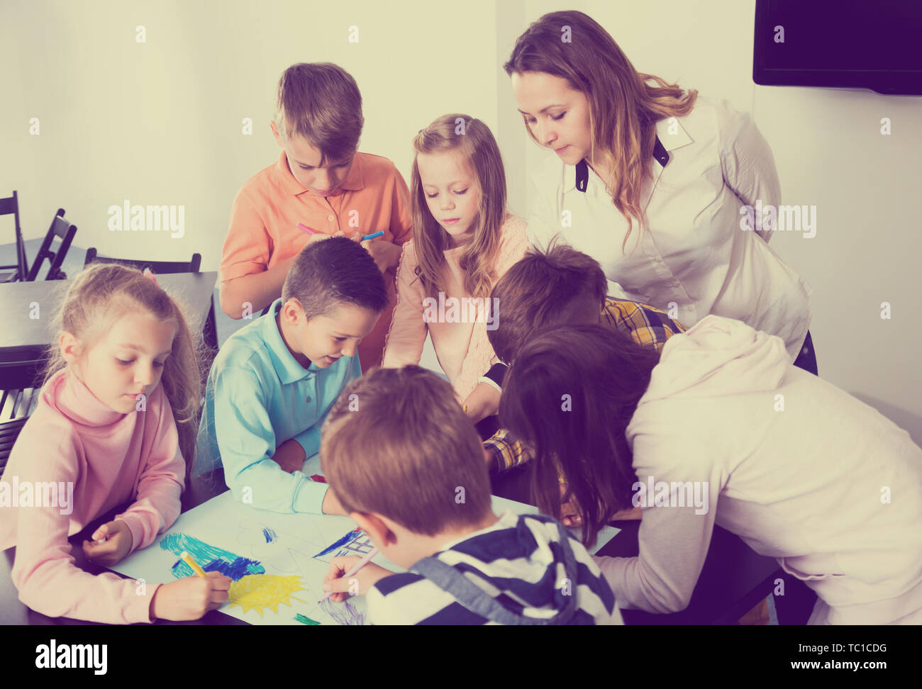 Team of elementary age children and beutiful teacher drawing on one ...
