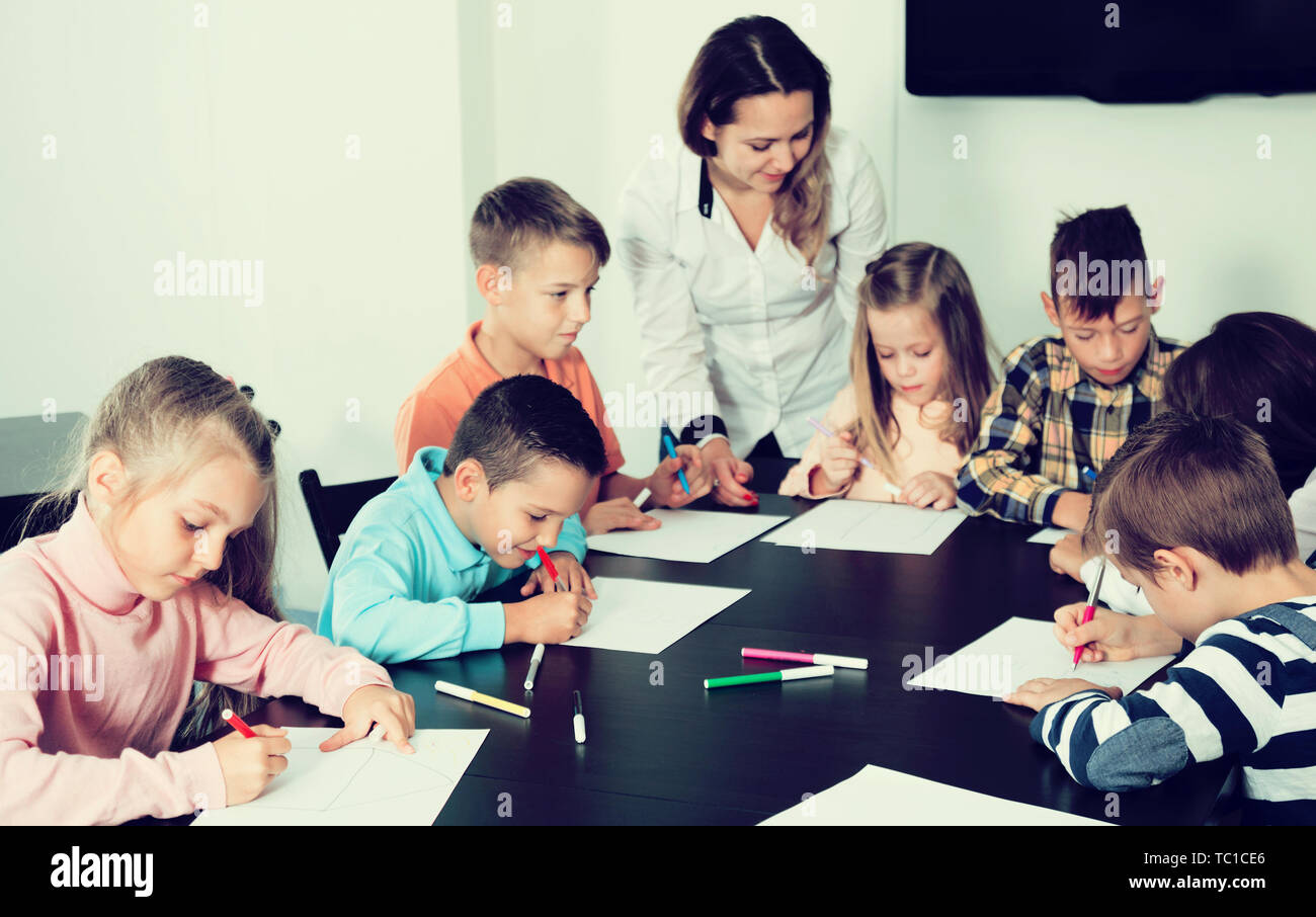 Glad little boys and girls with teacher drawing in classroom Stock ...