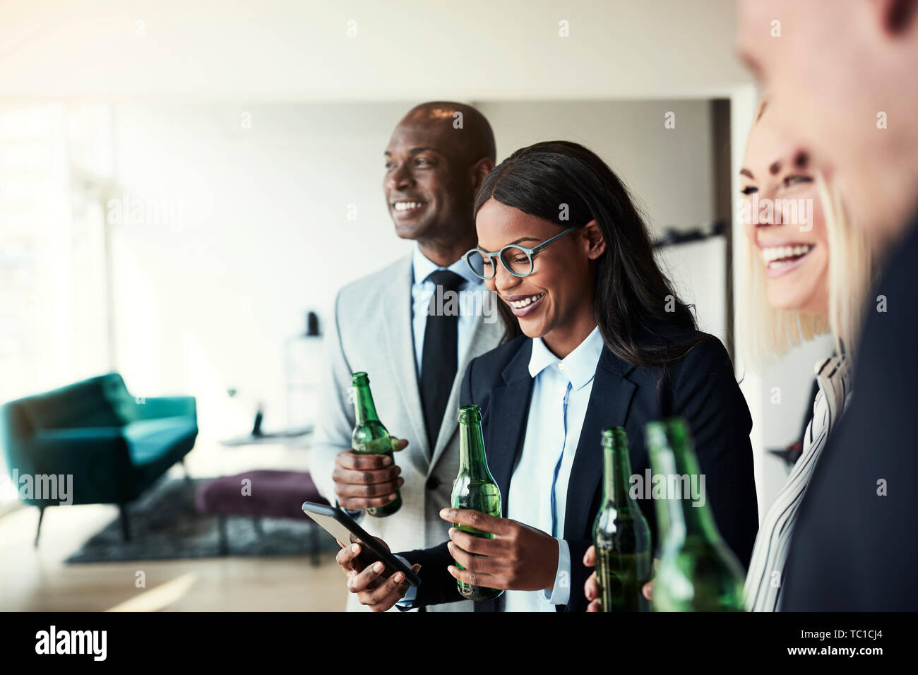 Smiling young African American businesswoman checking her cellphone during  after work drinks with a diverse group of office colleagues Stock Photo -  Alamy