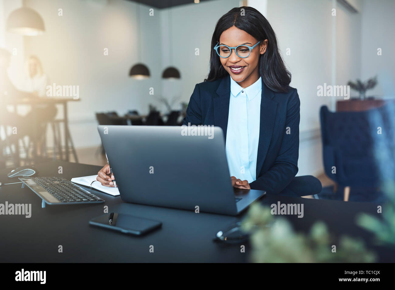 Smiling young African American businesswoman using a laptop while ...