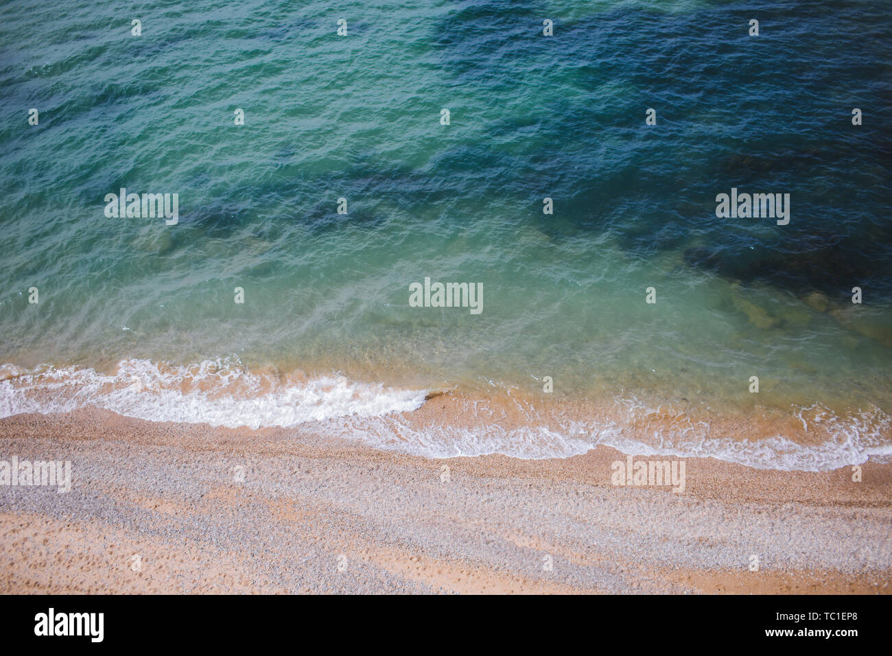 Clear blue water with waves washing the sandy shore. Top view ...