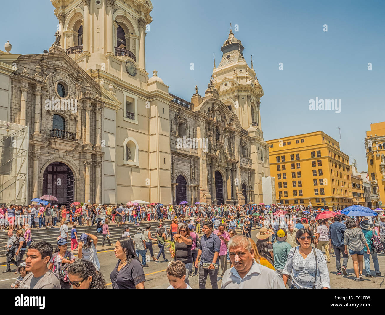 Lima, Peru - March 29, 2018: People with colorful umbrellas on a hot day on the street of Lima next to Parroquia del Sagrario. Easter time. Good Frida Stock Photo