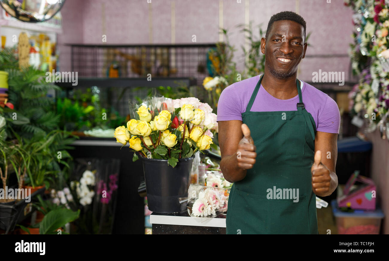 Satisfied successful African American male florist giving thumbs up at