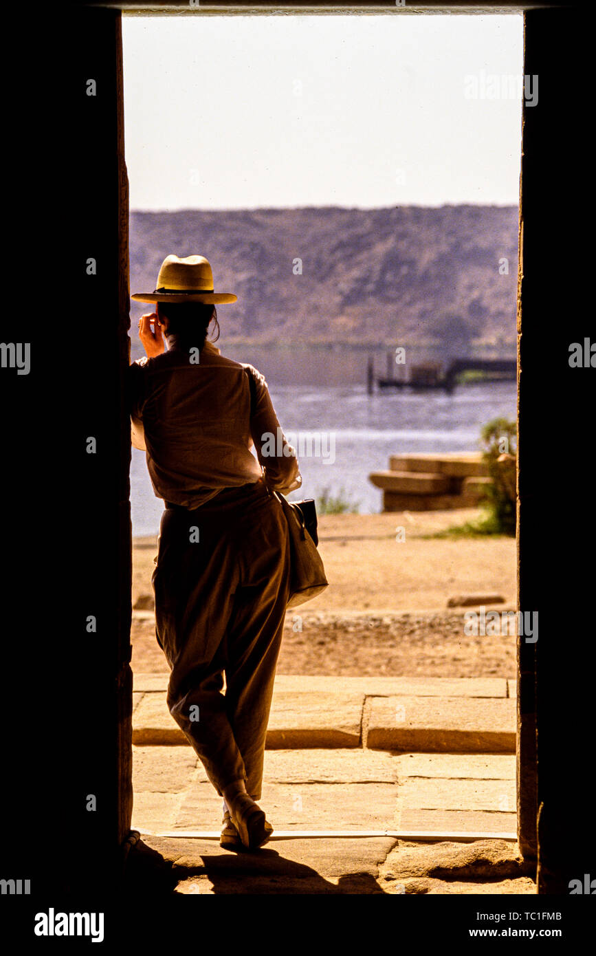 Photo: © Simon Grosset. A tourist looks across the Nile from Philae Temple, Aswan, Egypt. Archive: Image digitised from an original transparency. Stock Photo