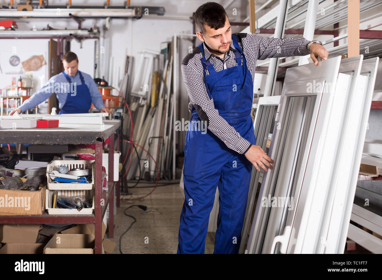Laborer is inspecting the window frame in workshop. Stock Photo