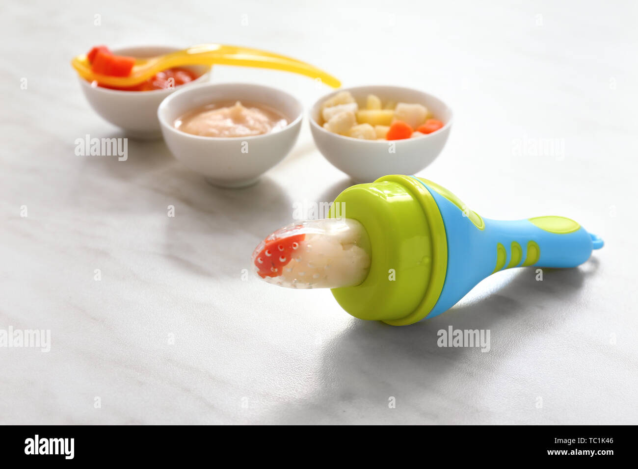 Baby nibbler with fresh food on light table Stock Photo