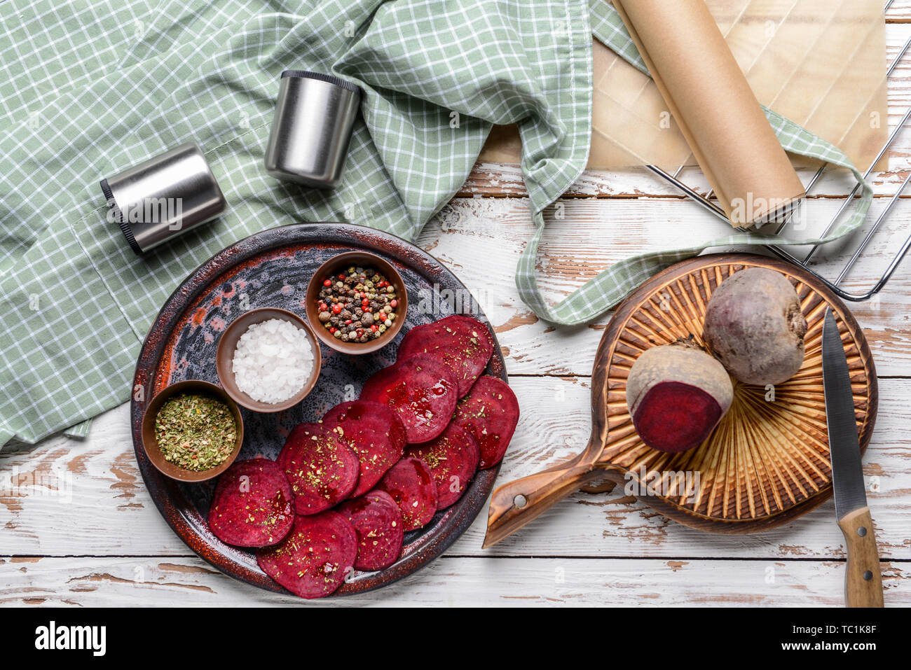 Plate with tasty raw beet chips and spices on wooden table Stock Photo