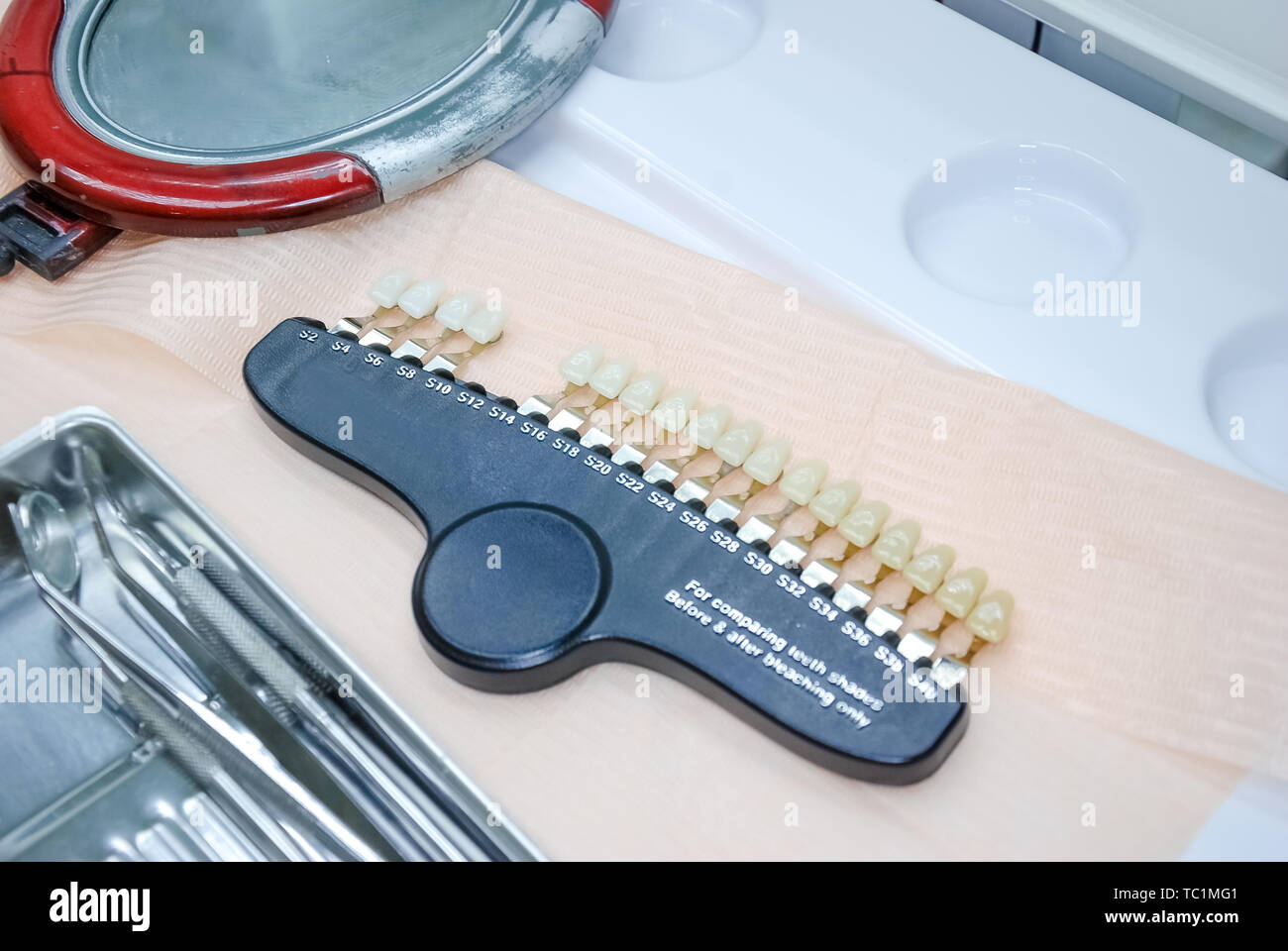 Dentist checking and selecting color of young man's teeth, closeup