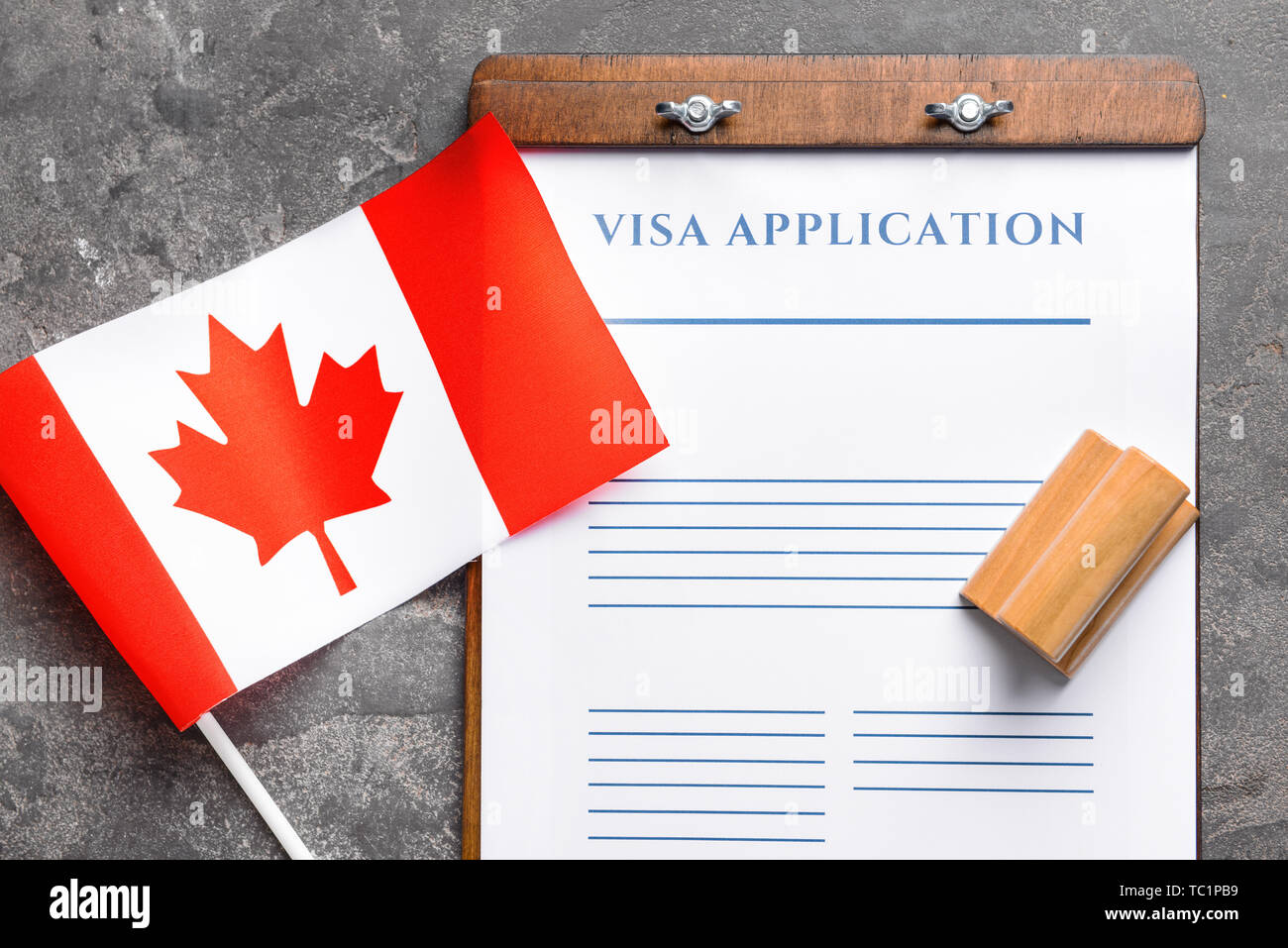 Visa application form, stamp and Canadian flag on table. Concept of immigration Stock Photo