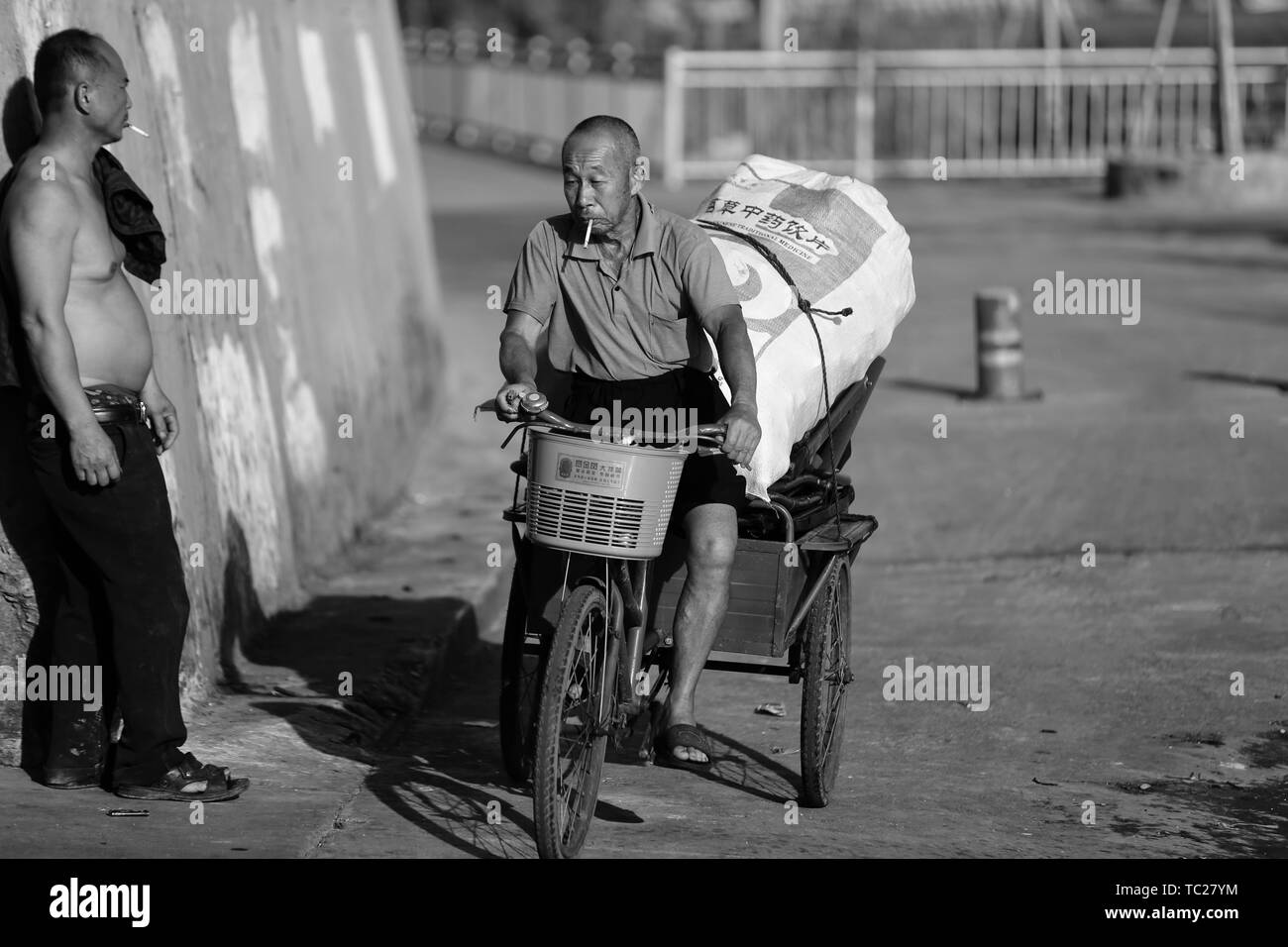 In the corner of the street, the master on a tricycle and full of goods. Stock Photo