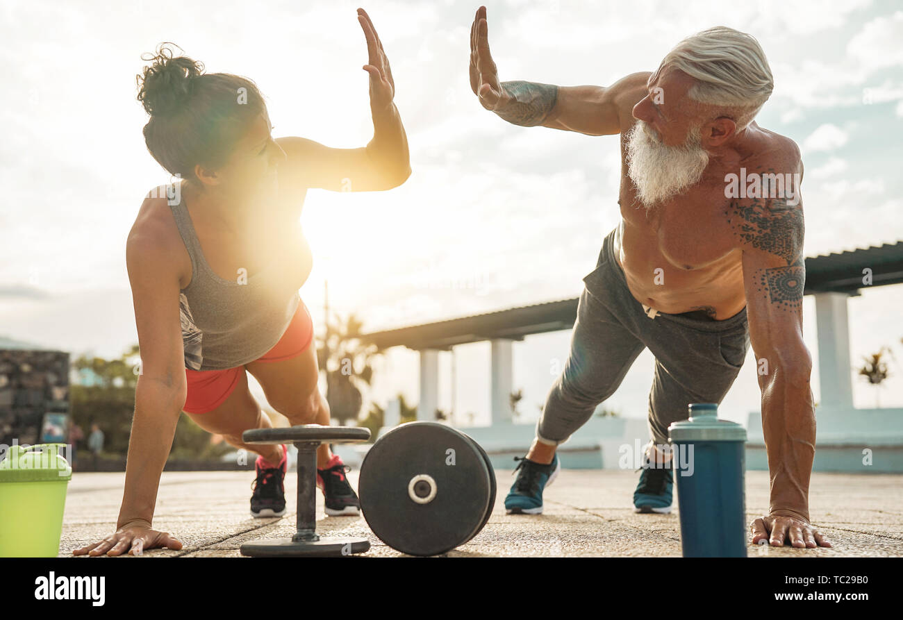 Fitness couple doing push ups exercise at sunset outdoor - Happy athletes making gym workout session outside Stock Photo