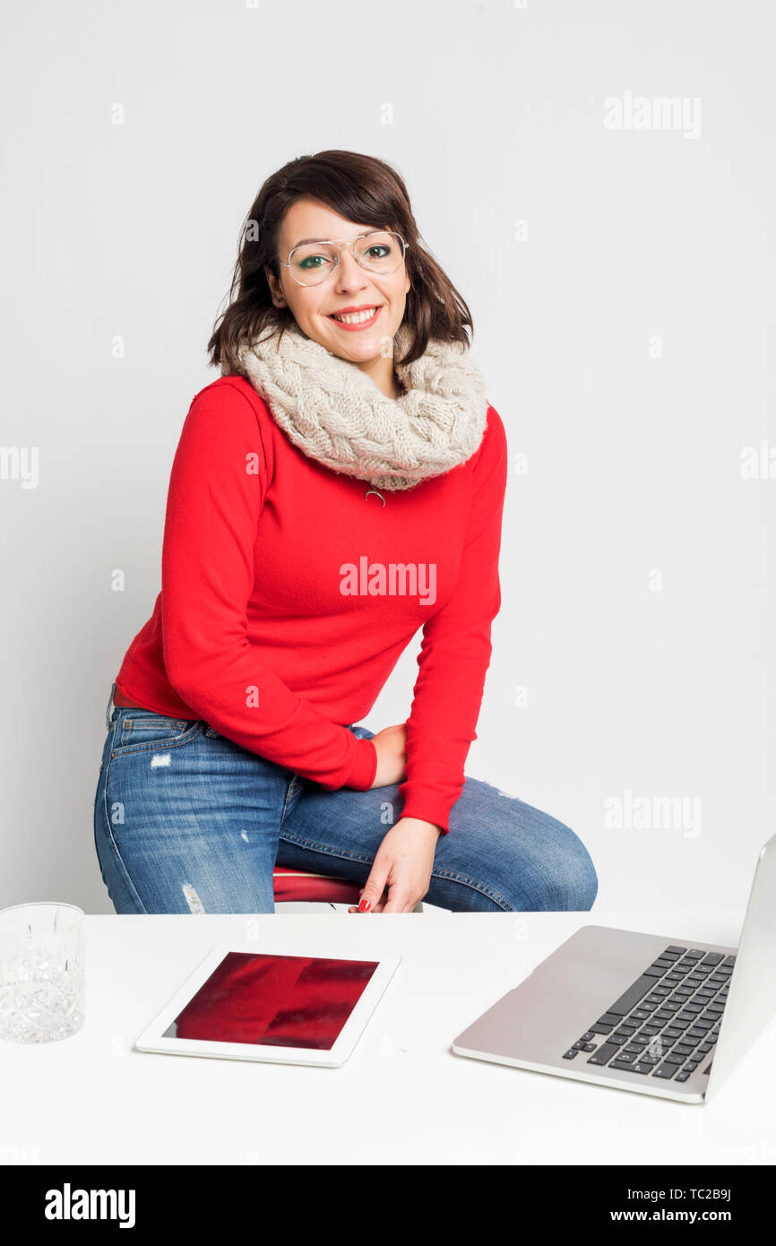 Front view of beautiful woman in casual wear sitting on a stool while looking camera against white background Stock Photo