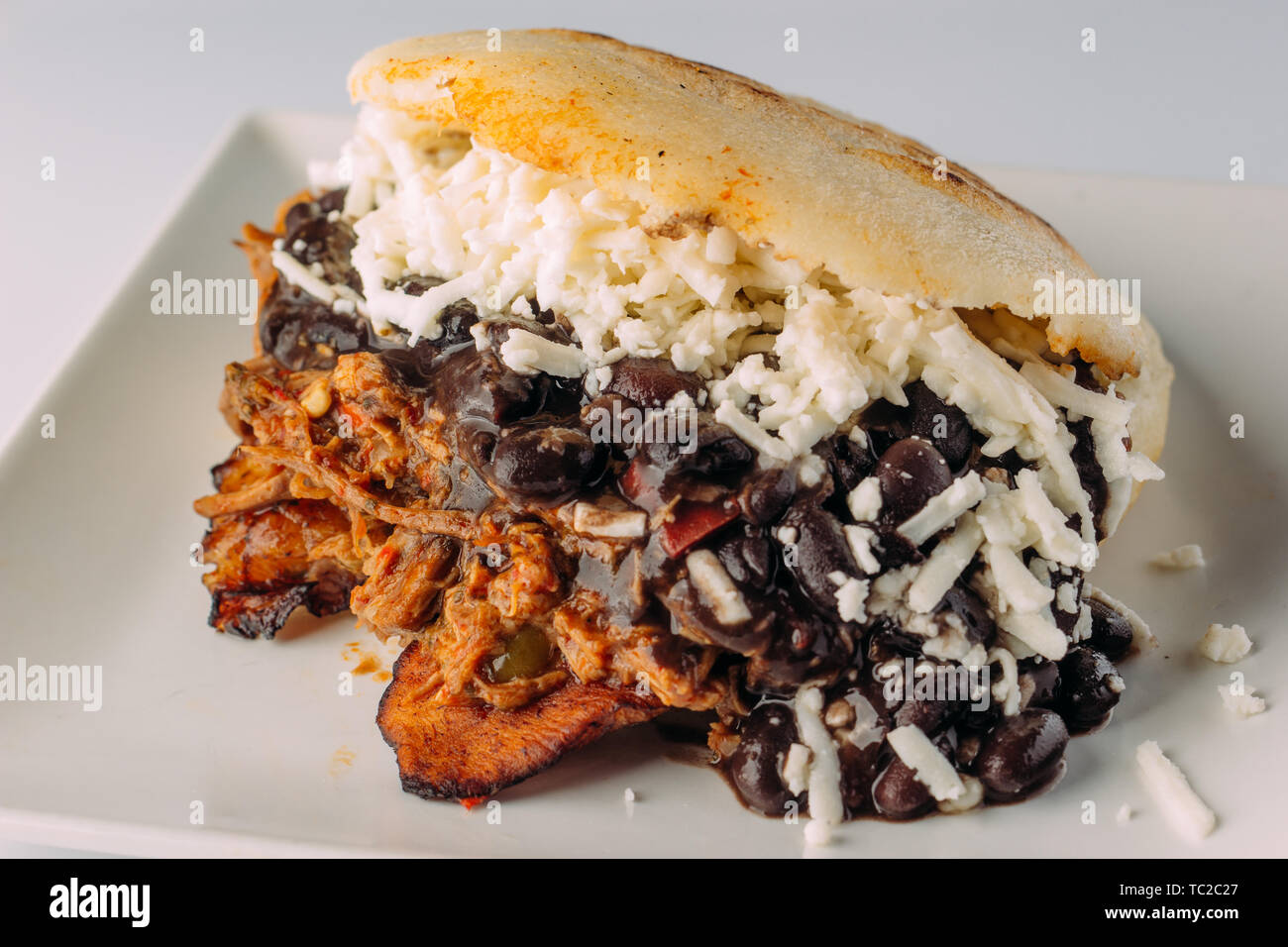 Arepa typical of Venezuela, Pabellon criollo, stuffed with fried plantain, white cheese, mechada meat and black beans Stock Photo