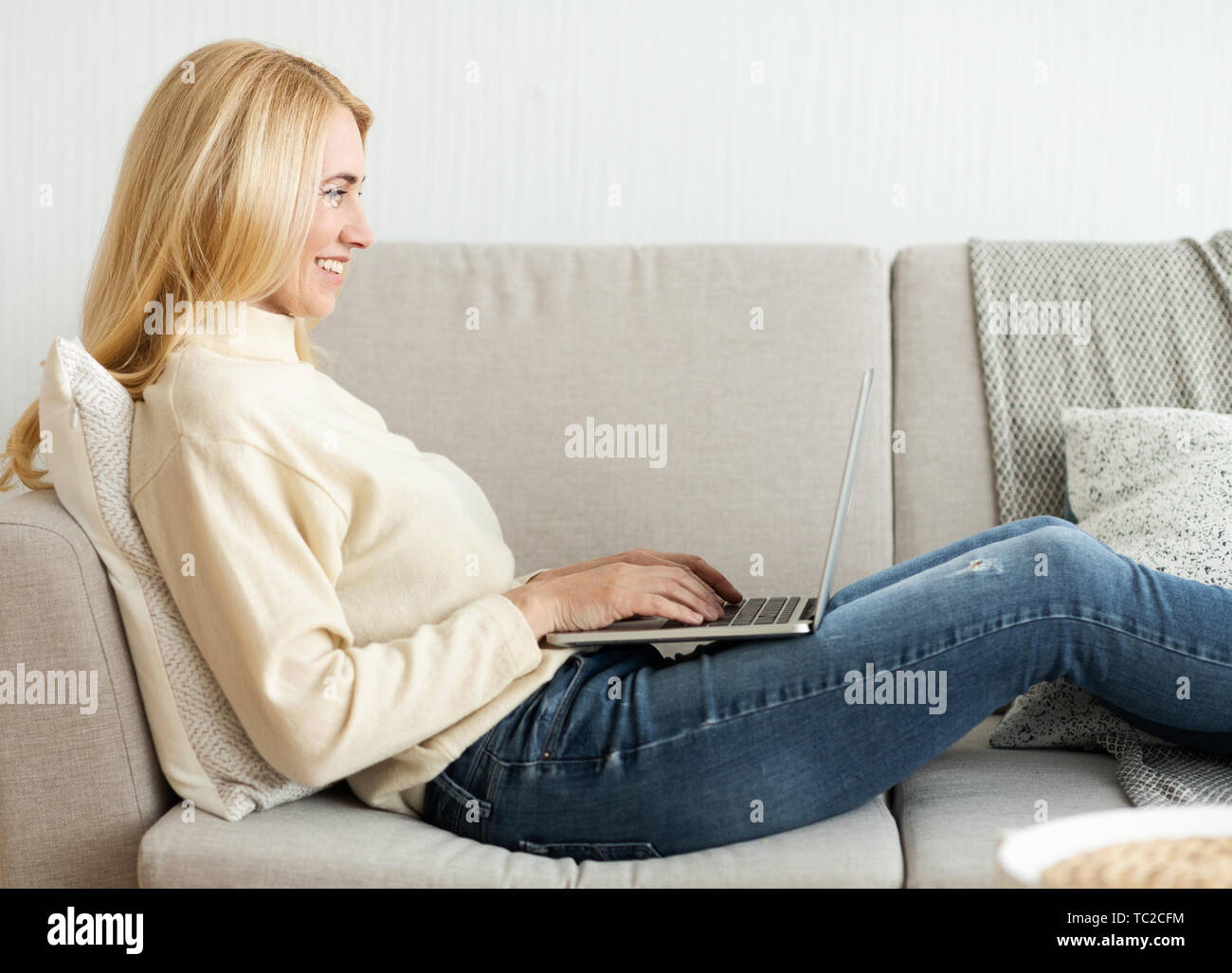 Smiling Woman Relaxing At Home With Laptop Stock Photo - Alamy